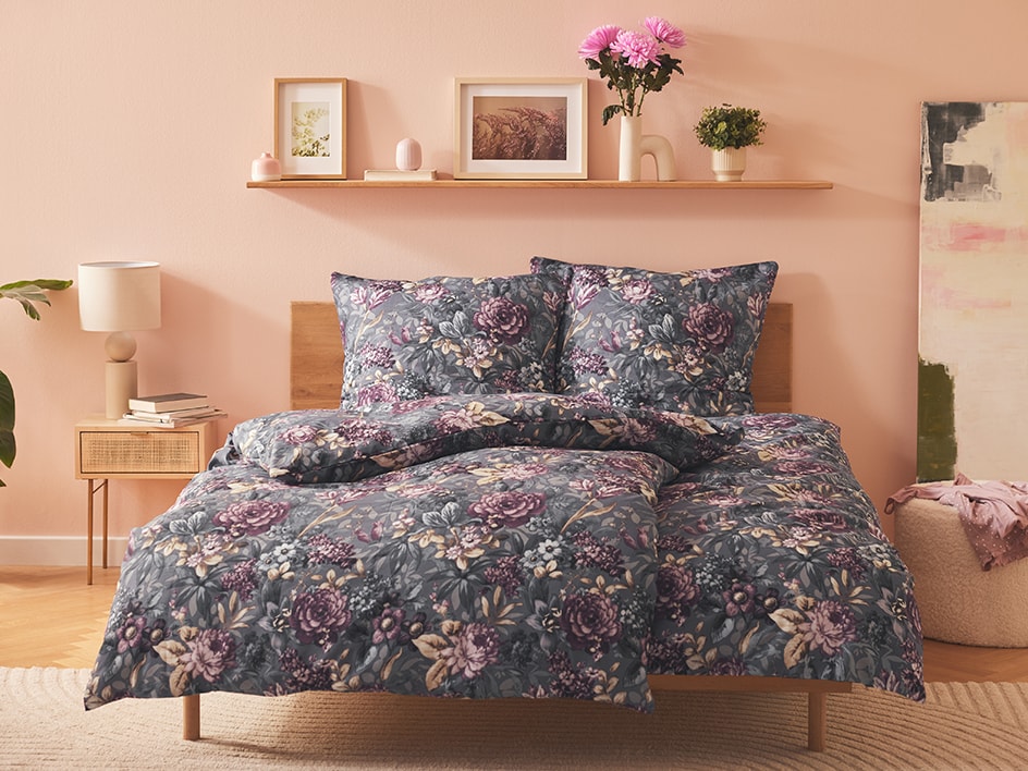 Dunkelgraues Blumen-Bettwäsche-Set auf hellem Holzbett.