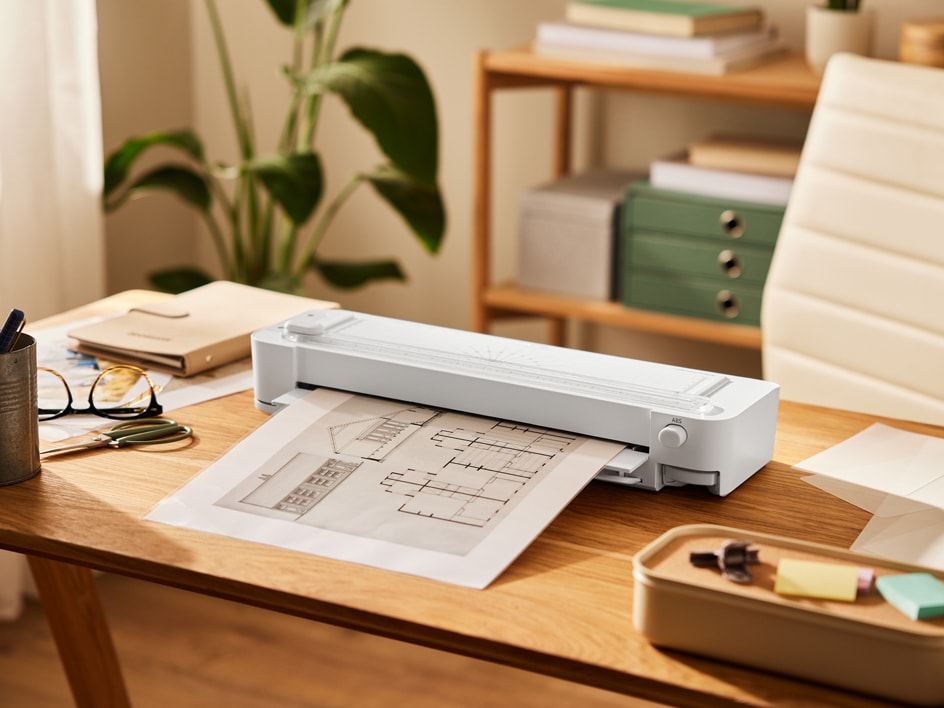 Ein weißer HP-Scanner scannt Architekturpläne auf einem Holztisch.