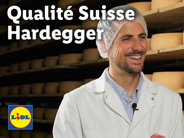 Lächelnder Mann in einem Käselager mit Lidl-Logo und dem Text „Qualité Suisse Hardegger“.