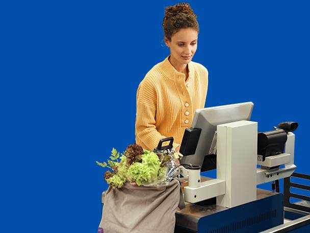 Frau an der Selbstbedienungskasse mit frischem Gemüse in einer wiederverwendbaren Tasche.