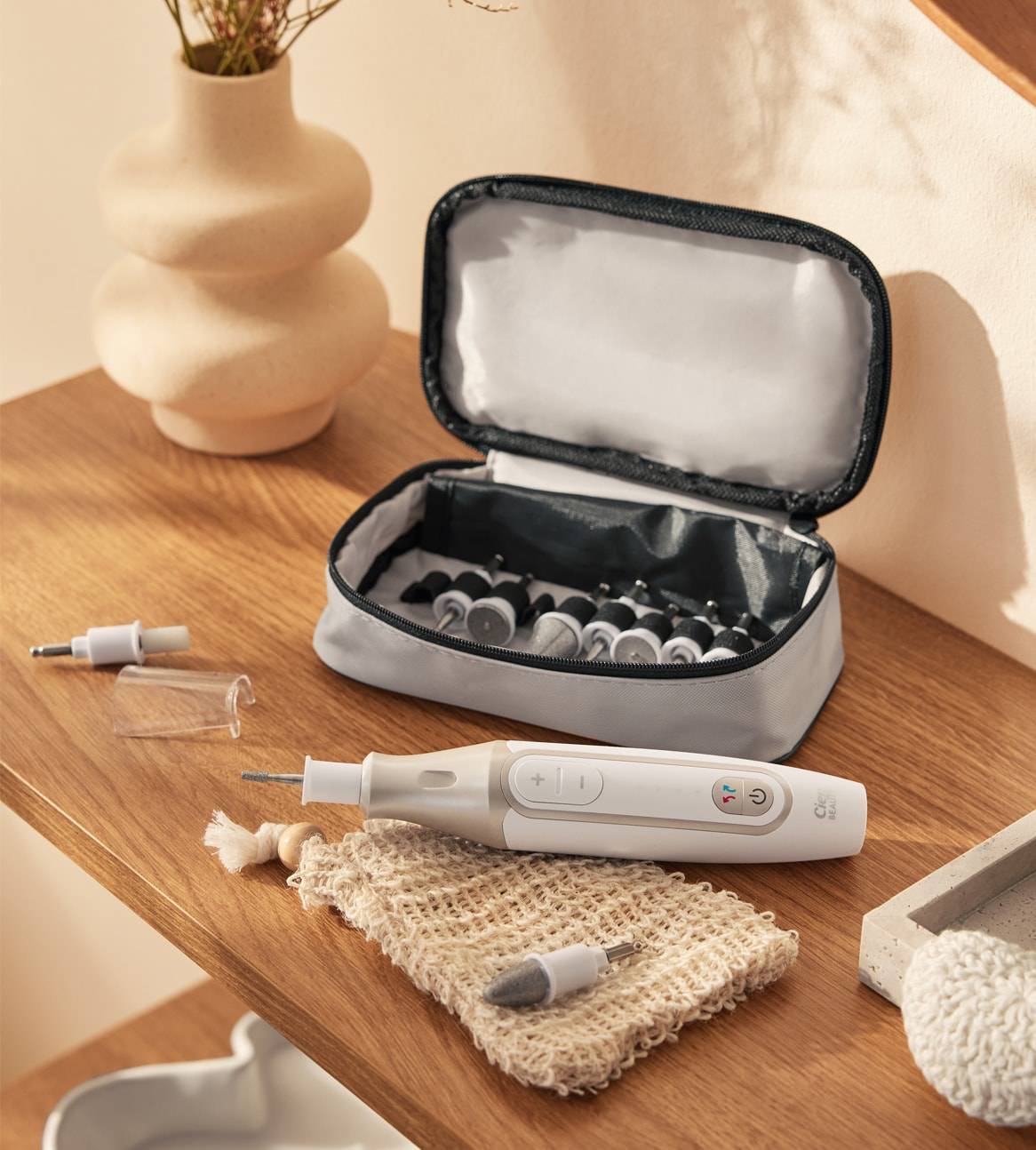 Un kit de manucure et pédicure avec étui, perceuse électrique et accessoires sur une table en bois.