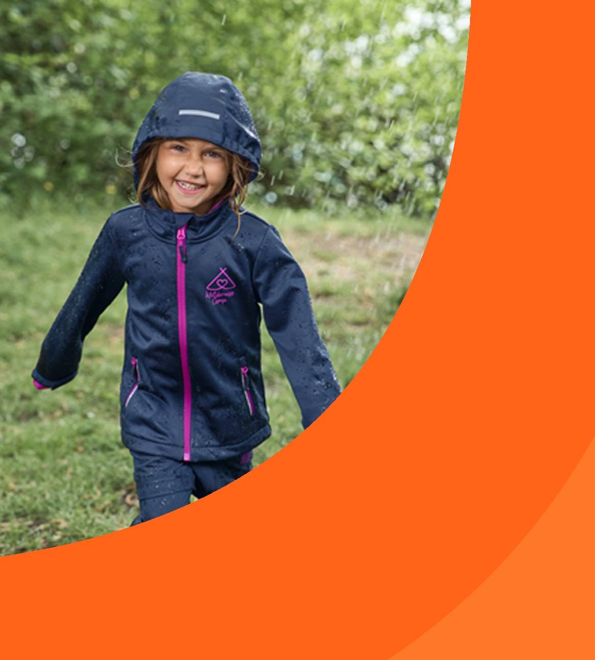 Bambina sorridente in abbigliamento impermeabile da esterno sotto la pioggia.