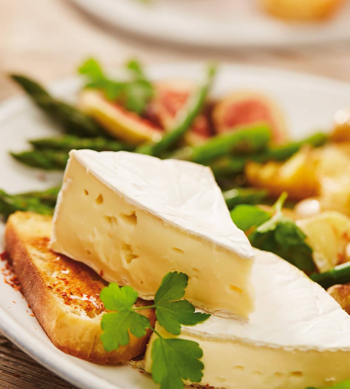 Brie-Scheibe auf Toast mit Spargel und Feigen.