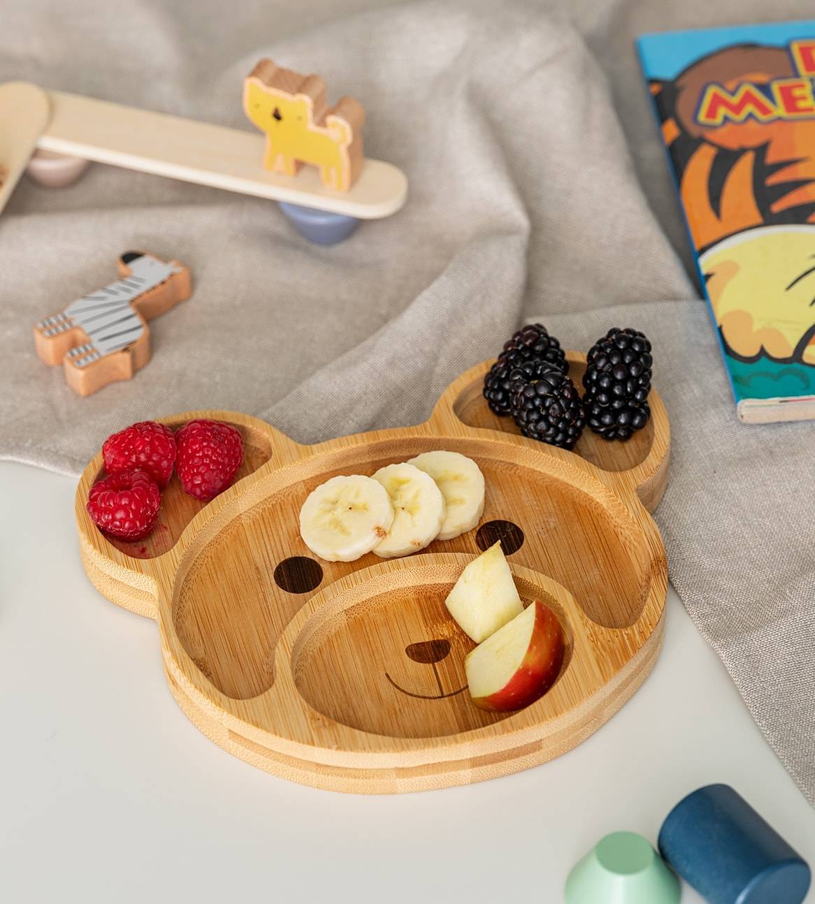 Ein Bambus-Kinderteller in Bärenform mit Obst und Beeren.