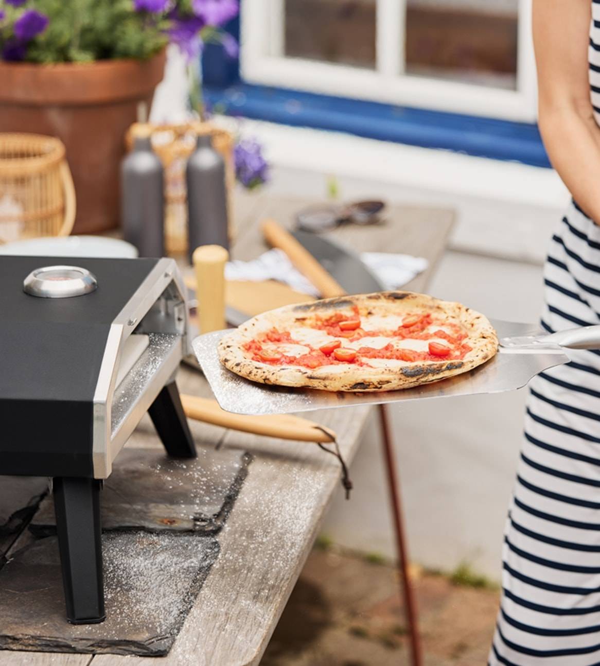 Eine Pizza wird aus einem tragbaren Pizzabackofen genommen.