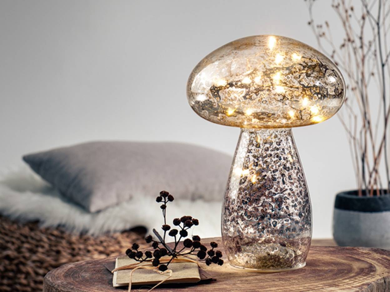Lampada a fungo in vetro mercurio illuminata su un tavolino di legno.