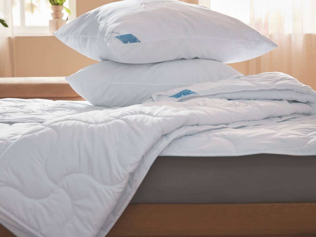 Weiße Kissen und eine Steppdecke liegen auf einem Bett.
