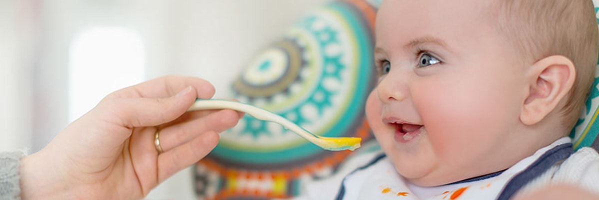 Bébé mange de la purée à la cuillère.