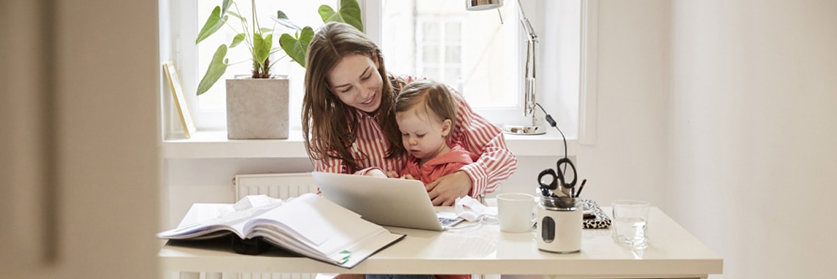 Une mère travaille sur un ordinateur portable avec son enfant.