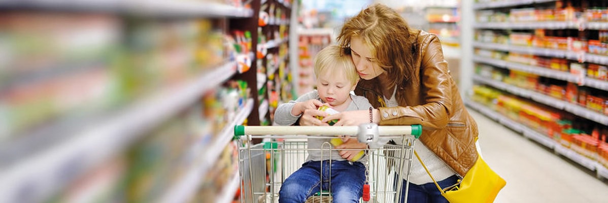 Mamma e bambino al supermercato con un carrello.