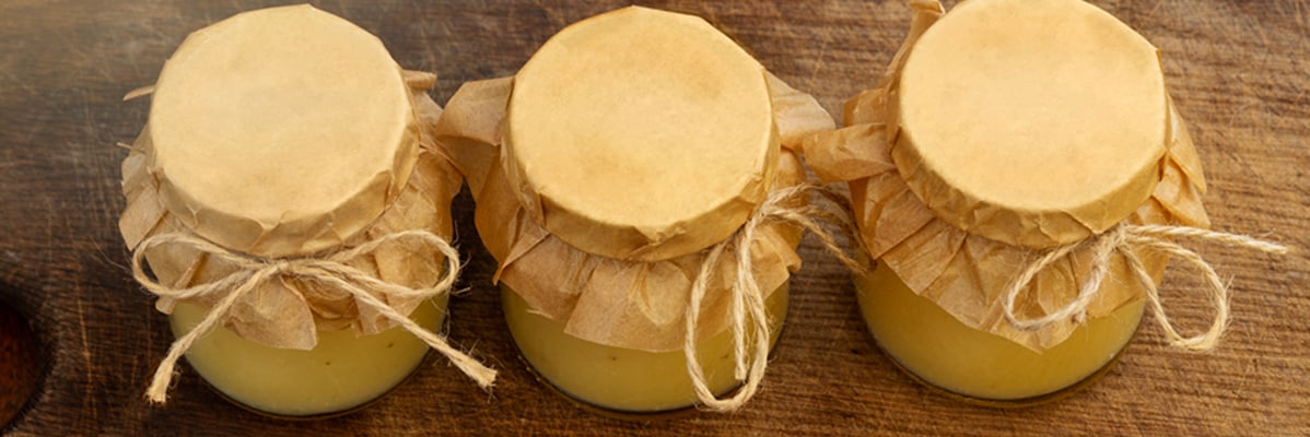 Trois pots de confiture, enveloppés dans du papier kraft.