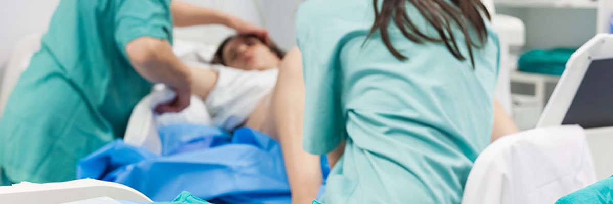 Femme en train d'accoucher, assistée par des sages-femmes.