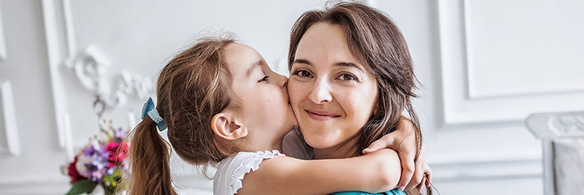 Eine Mutter umarmt ihre Tochter zärtlich.