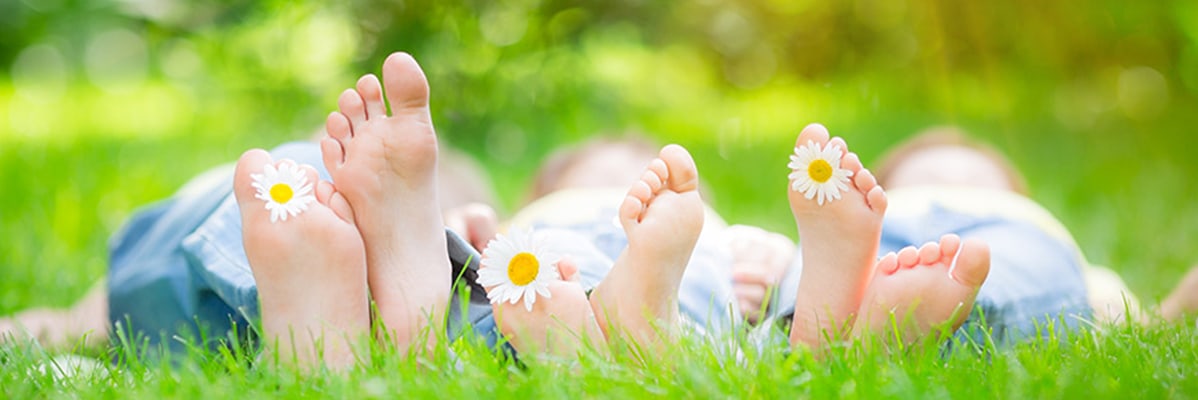 Piedini di bambini nell'erba con margherite.