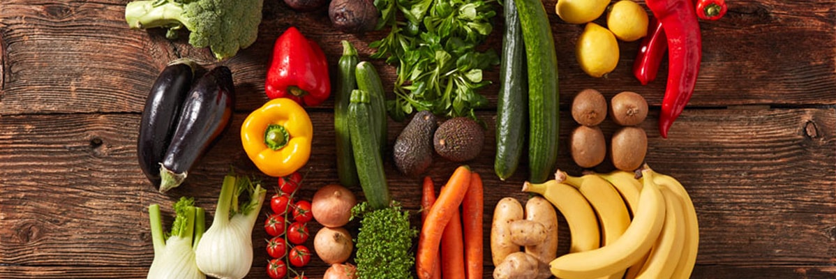 Banane, verdure e frutta su superficie di legno.