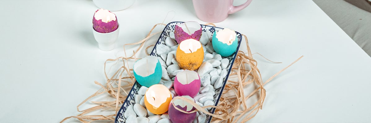 Candele di Pasqua colorate a forma d'uovo in un piatto decorativo.