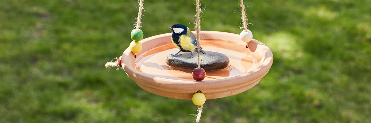 Un bagno per uccelli in terracotta con un piccolo uccellino.