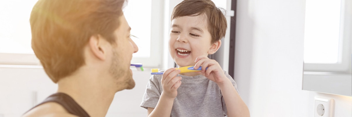 Vater und Sohn putzen sich die Zähne.