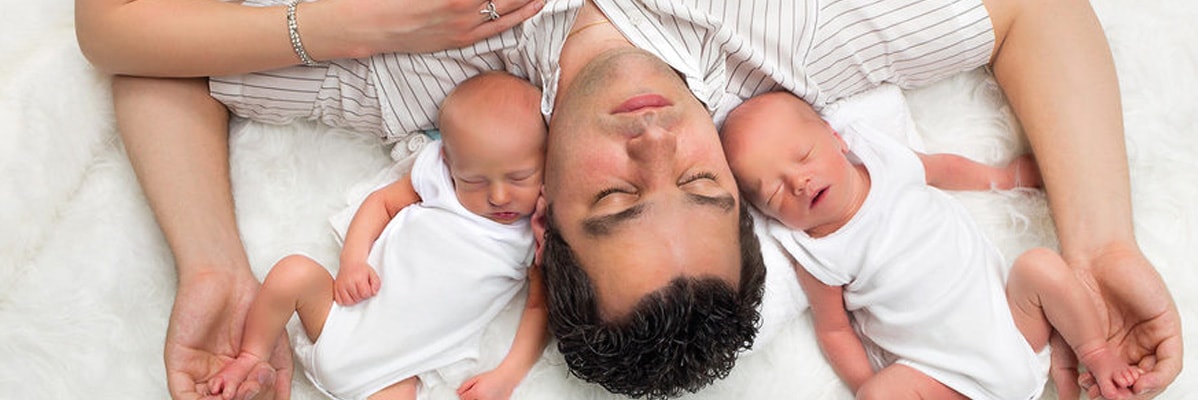 Padre che dorme con i suoi gemelli neonati.