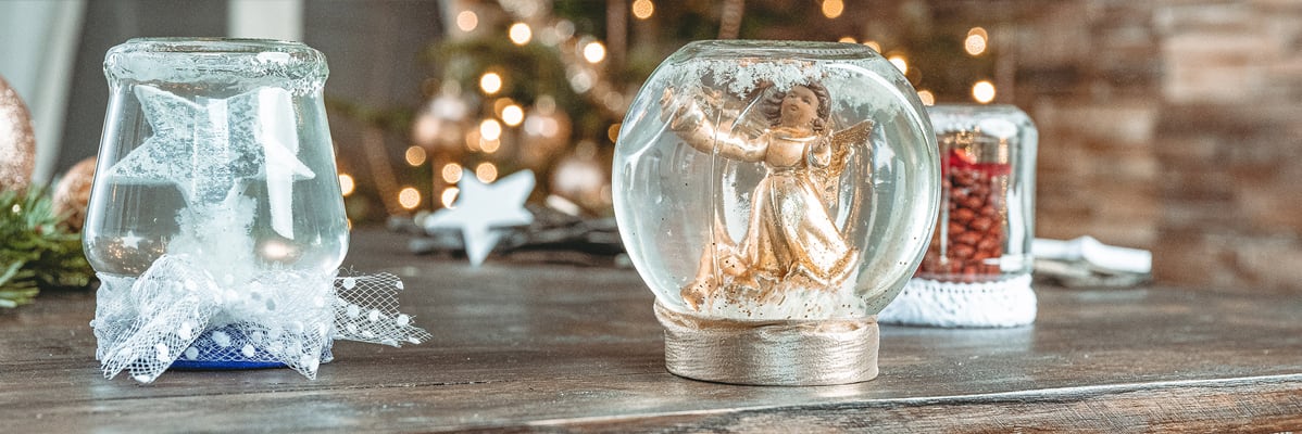 Sfere di neve natalizie con angelo e barattoli decorati.