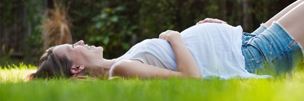 Femme enceinte se détendant sur l'herbe.