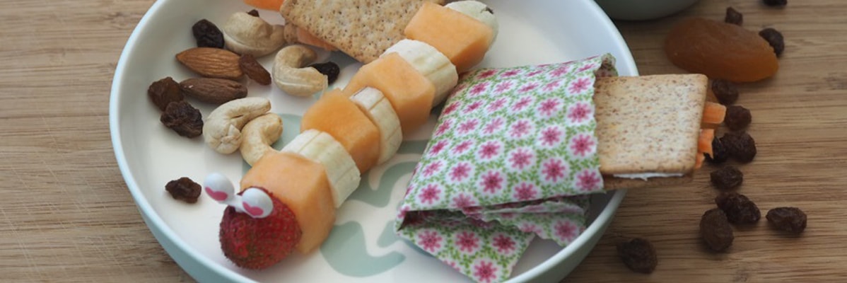 Frutta, cracker e frutta secca in un piatto per bambini.