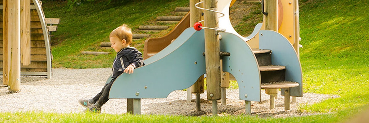 Bambino su uno scivolo e scale del parco giochi.