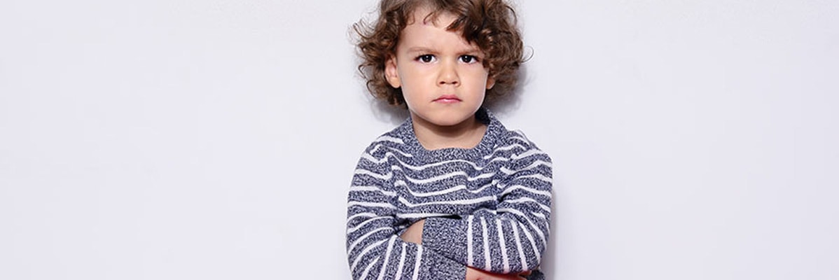Un jeune enfant en colère portant un pull rayé.