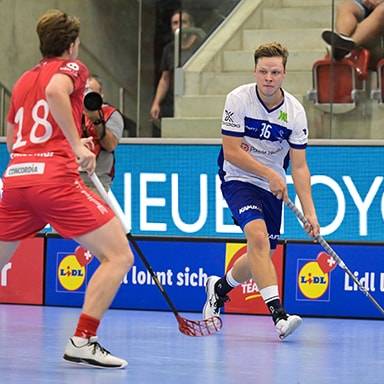 Due giocatori di floorball in azione su un campo con sponsorizzazioni Lidl.