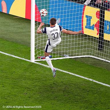 Ein Fußballspieler in weißem Trikot tritt den Ball nahe dem Tor.