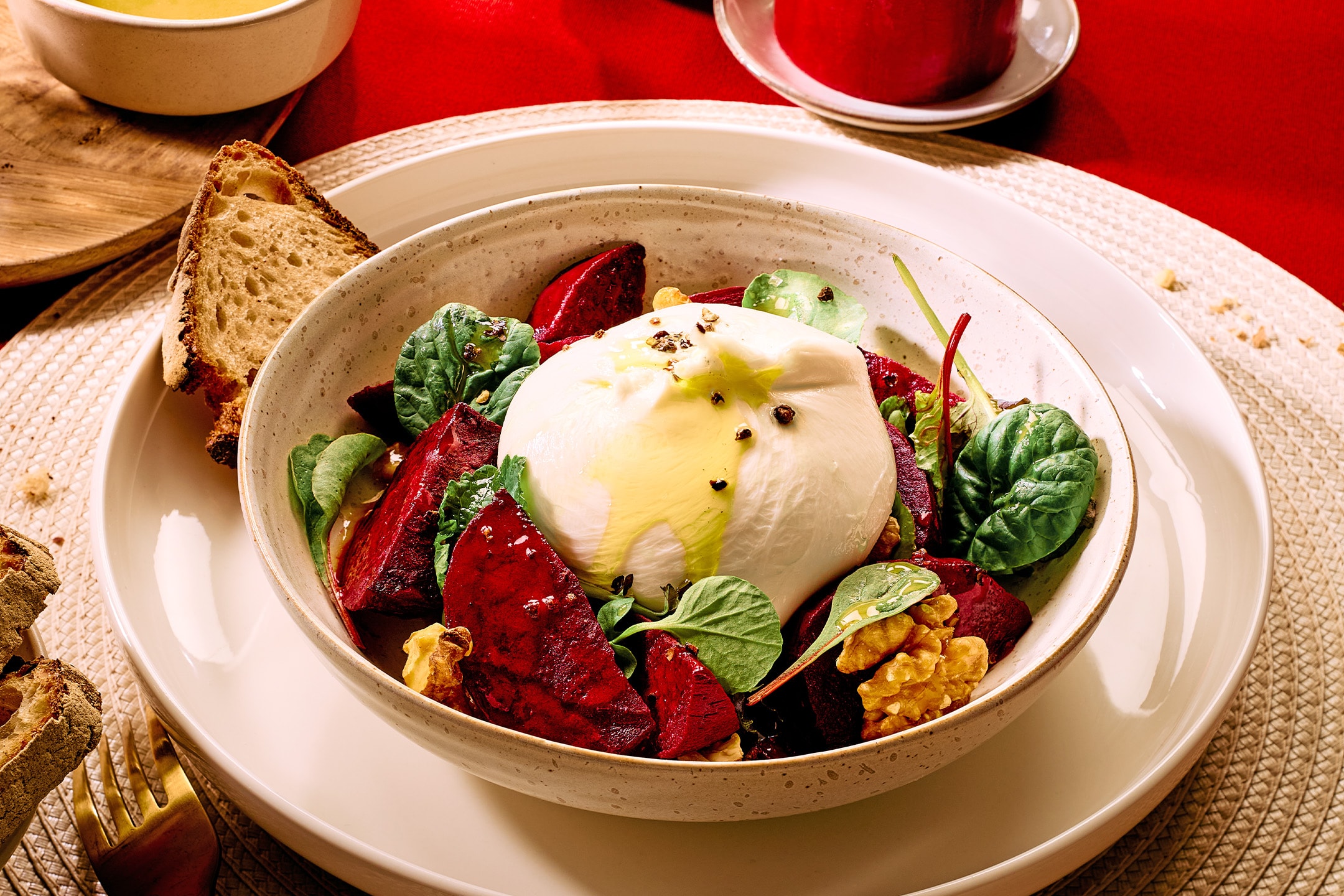 Burrata-Salat mit Roter Bete, Walnüssen und Blattsalat, dazu Brot und ein Getränk.