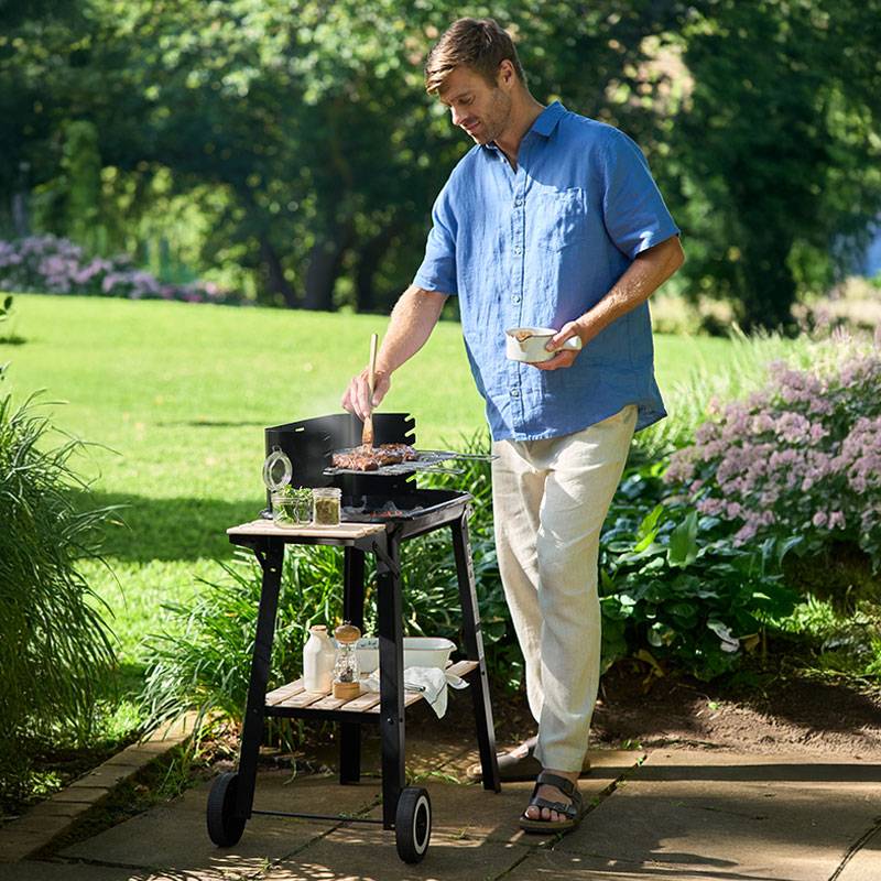Uomo che griglia bistecche su un barbecue da giardino.