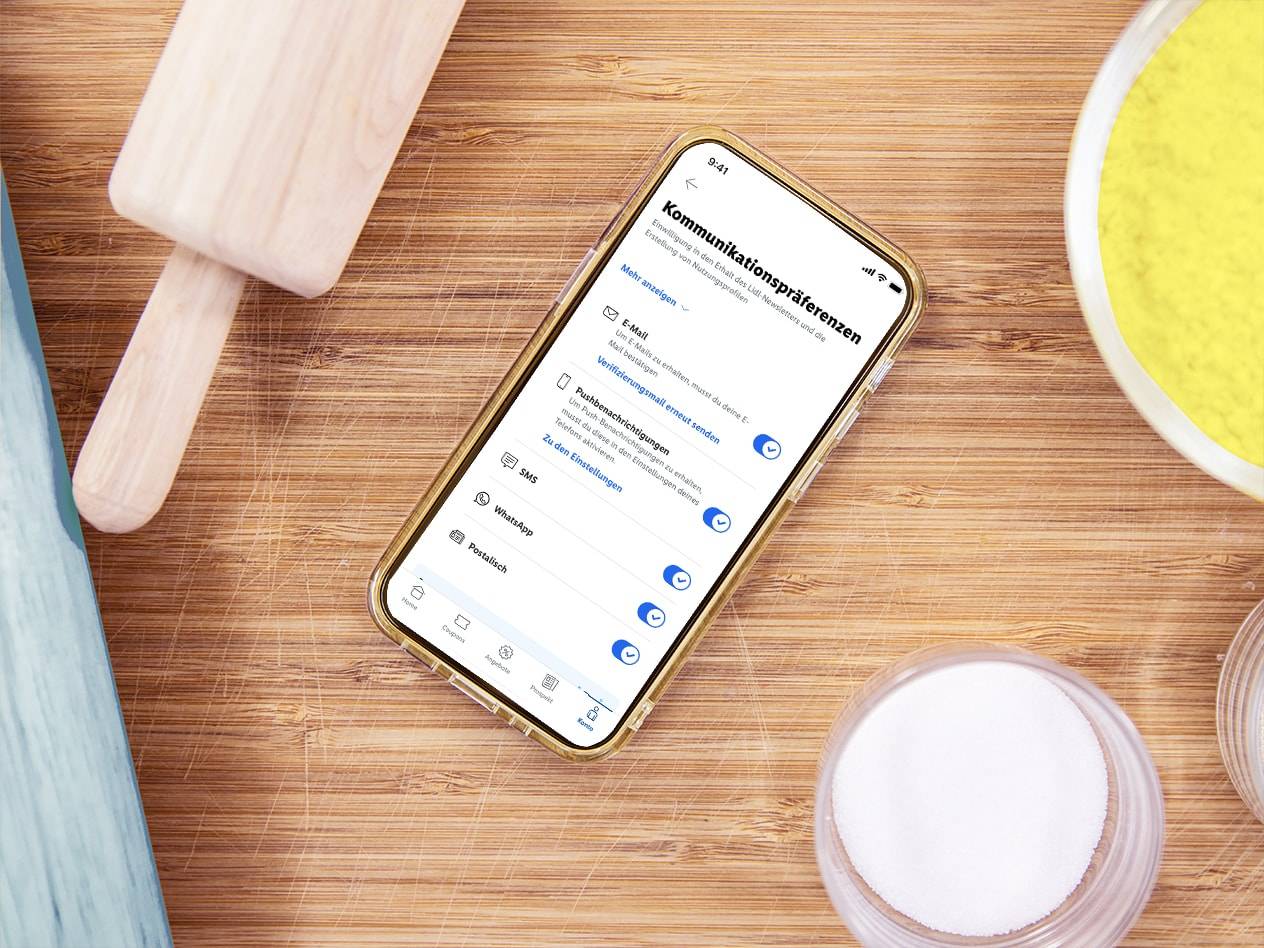 Ein Smartphone mit Lidl-Kommunikationspräferenzen auf einem Holzschneidebrett.