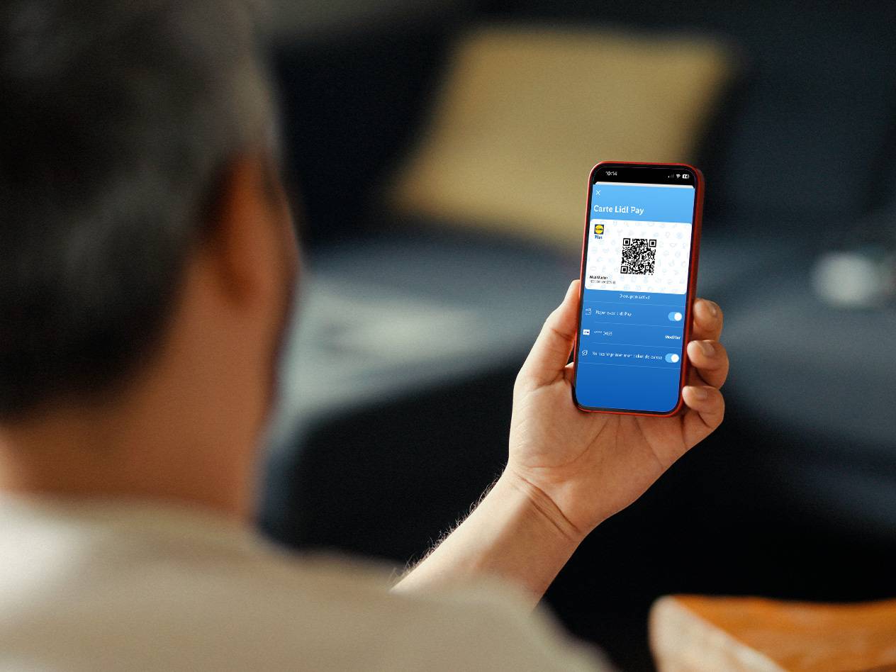 Une personne tient un smartphone affichant une carte de fidélité numérique et un code QR.