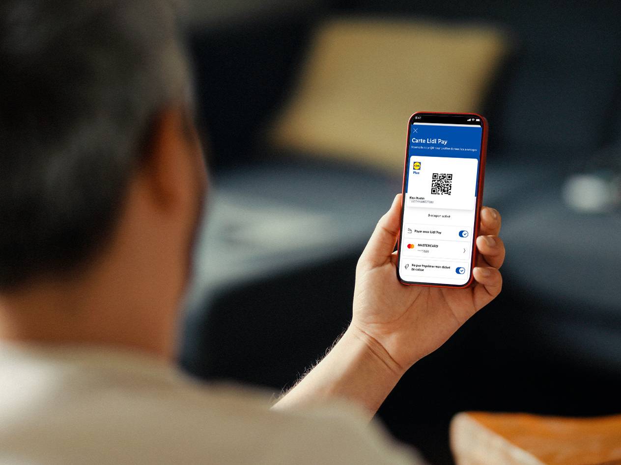 Une personne tient un smartphone affichant une carte de fidélité numérique et un code QR.