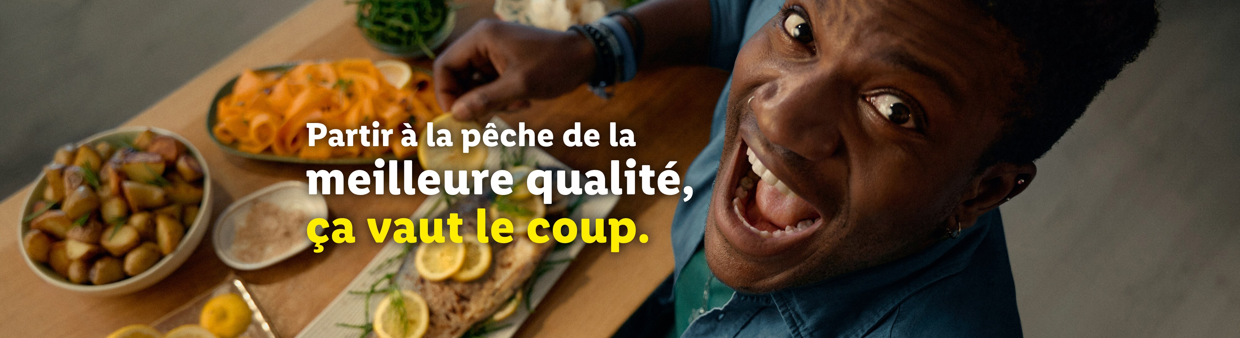 Un homme souriant avec un repas de poisson, pommes de terre et carottes.