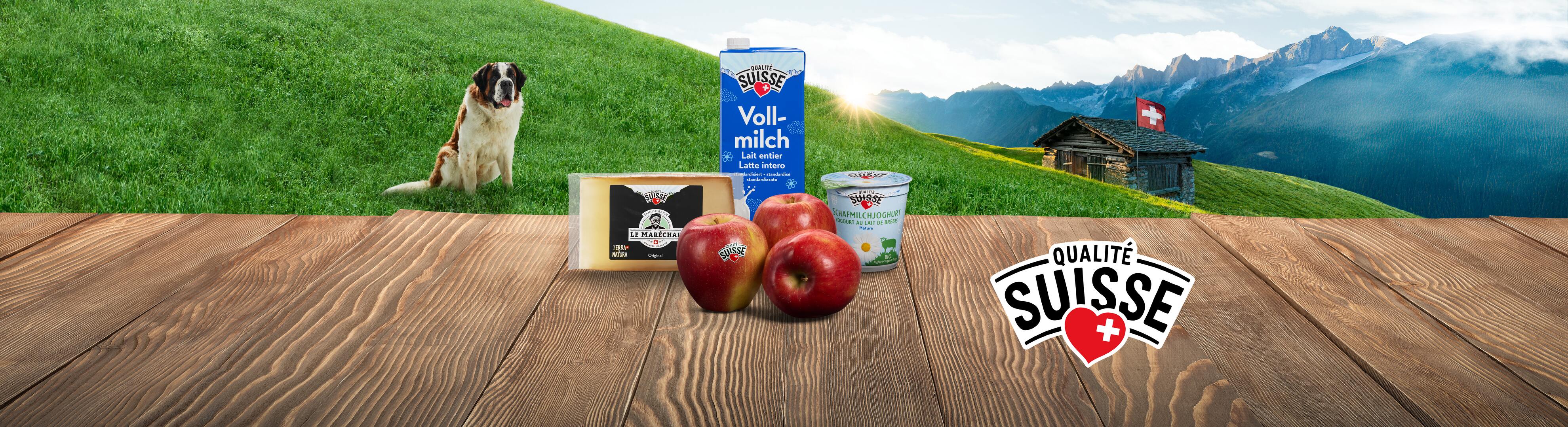Fromage Le Maréchal et lait Qualité Suisse sur une table en bois avec un chien Saint-Bernard et des montagnes.
