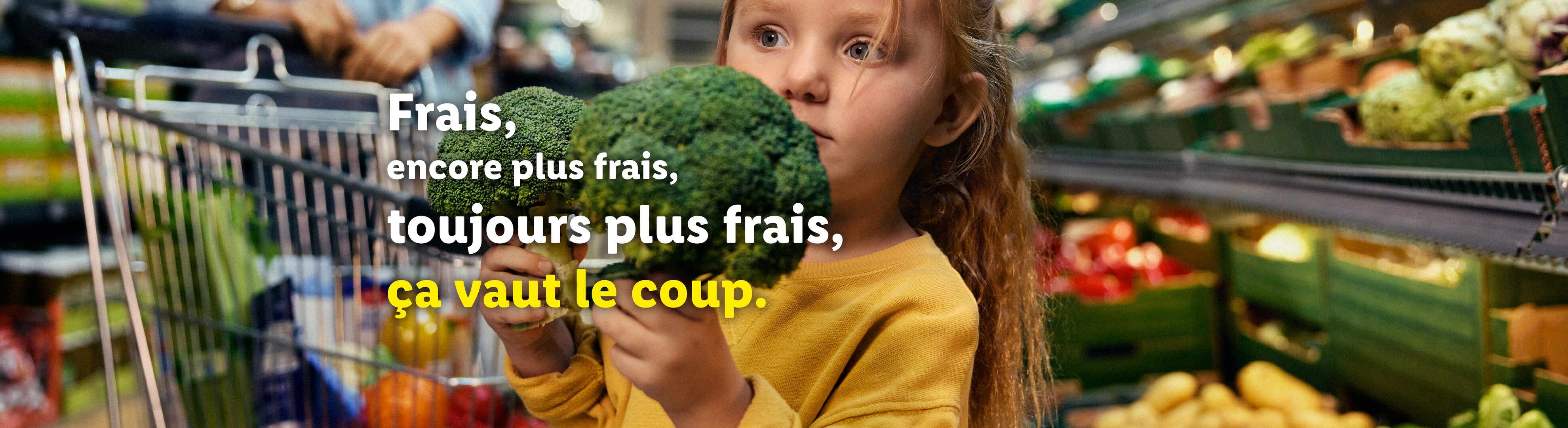 Petite fille avec du brocoli dans un supermarché, avec un texte promouvant la fraîcheur.