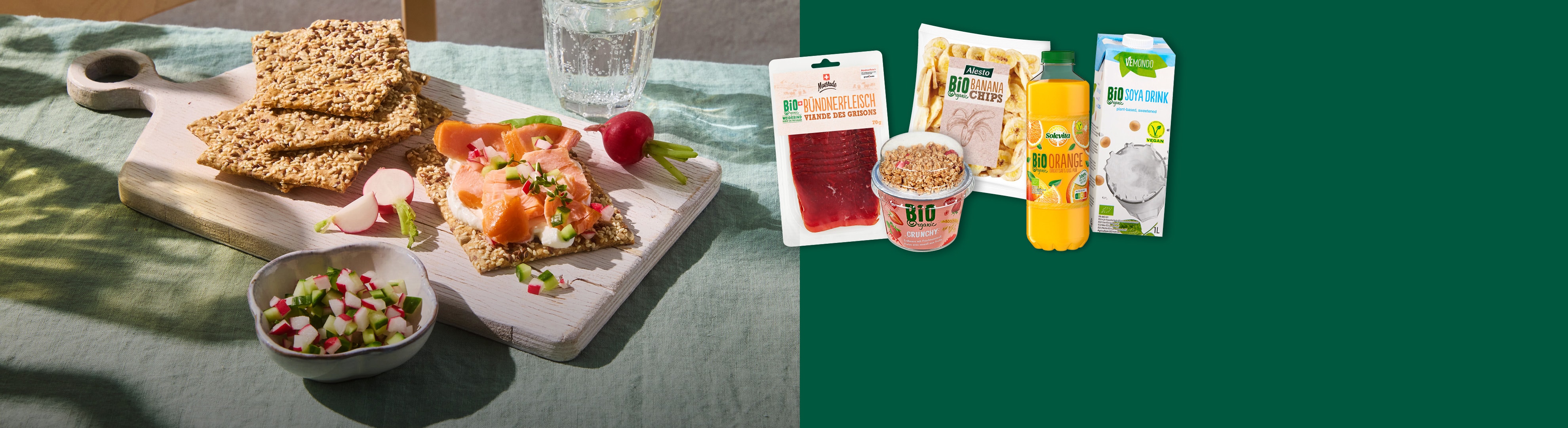 Knäckebrot mit Lachs und Radieschen, dazu Bio-Produkte wie Trockenfleisch, Bananenchips und Getränke.