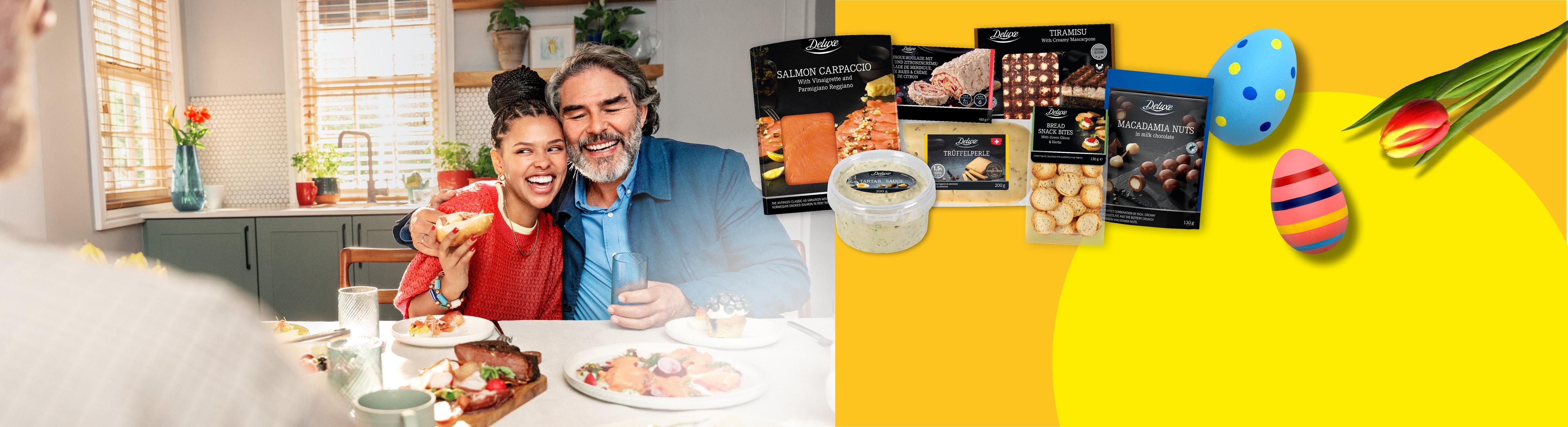 Ein lächelndes Paar beim Abendessen, mit Deluxe-Lebensmitteln und Ostereiern.