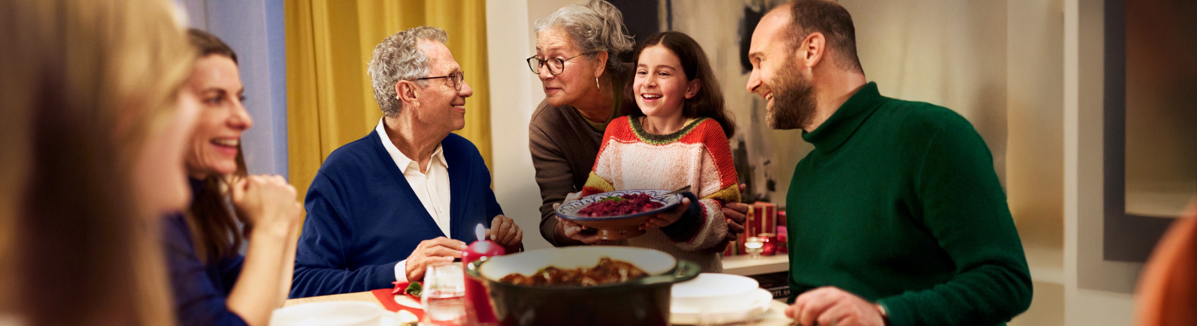 Familie versammelt sich am Tisch für ein festliches Abendessen mit Speisen und Dekorationen.