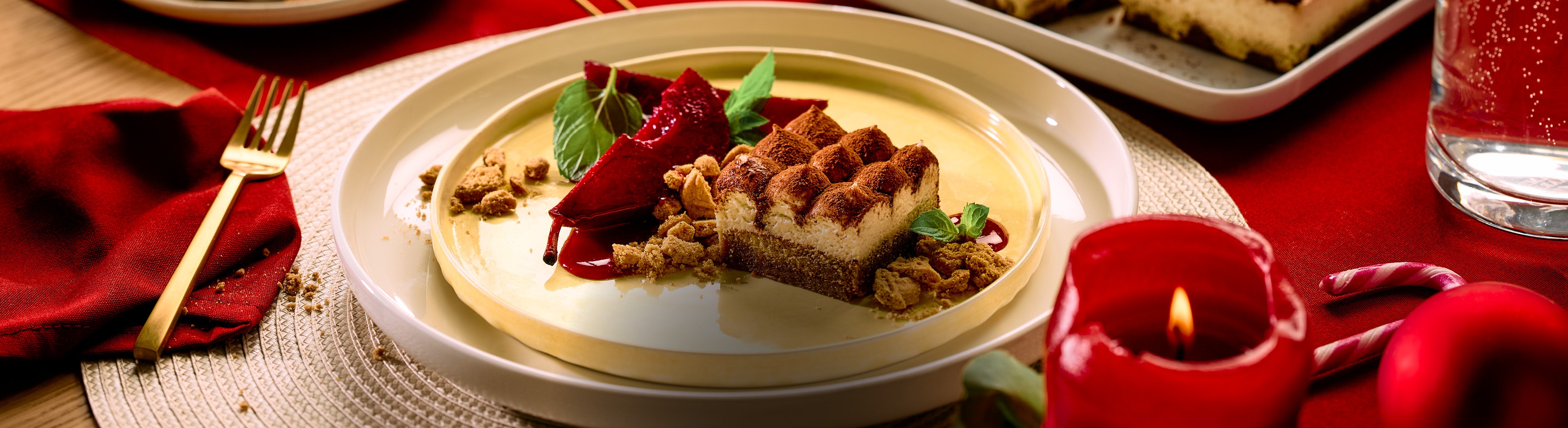 Weihnachtsdessert mit Schokoladenkuchen und pochierten Birnen auf einem roten Tisch.