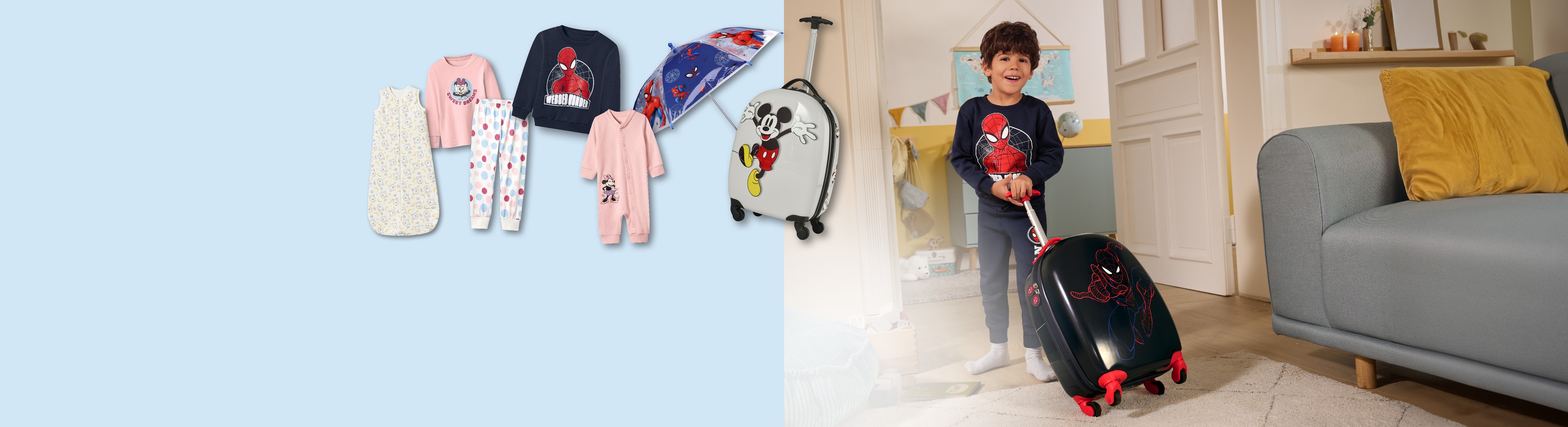 Junge mit Spiderman-Koffer, daneben Babykleidung, Schlafanzüge und ein Mickey Maus-Koffer.