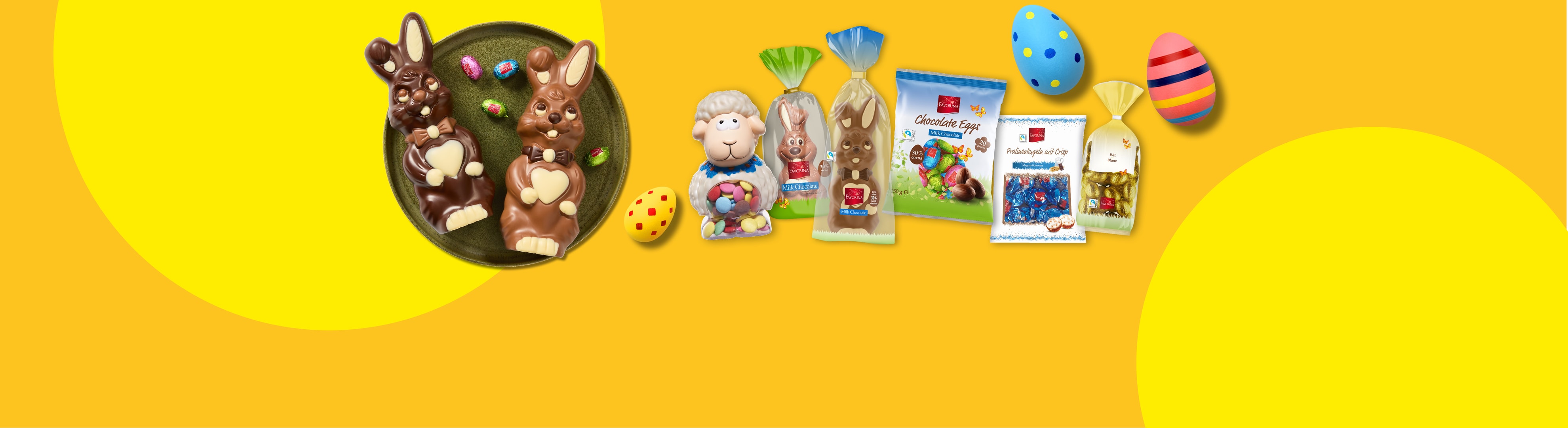 Osterhasen, Schokoladeneier und Pralinen vor gelbem Hintergrund.