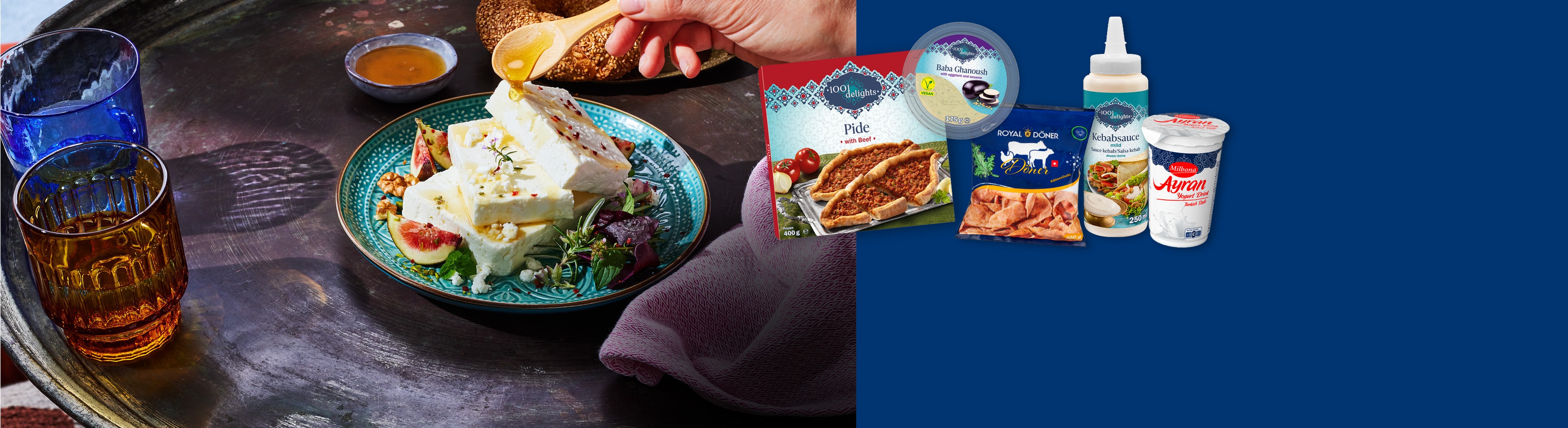 Spécialités turques comme le pide, le döner, le baba ghanoush, la sauce kebab et l'ayran, à côté d'une assiette de feta, figues et miel.