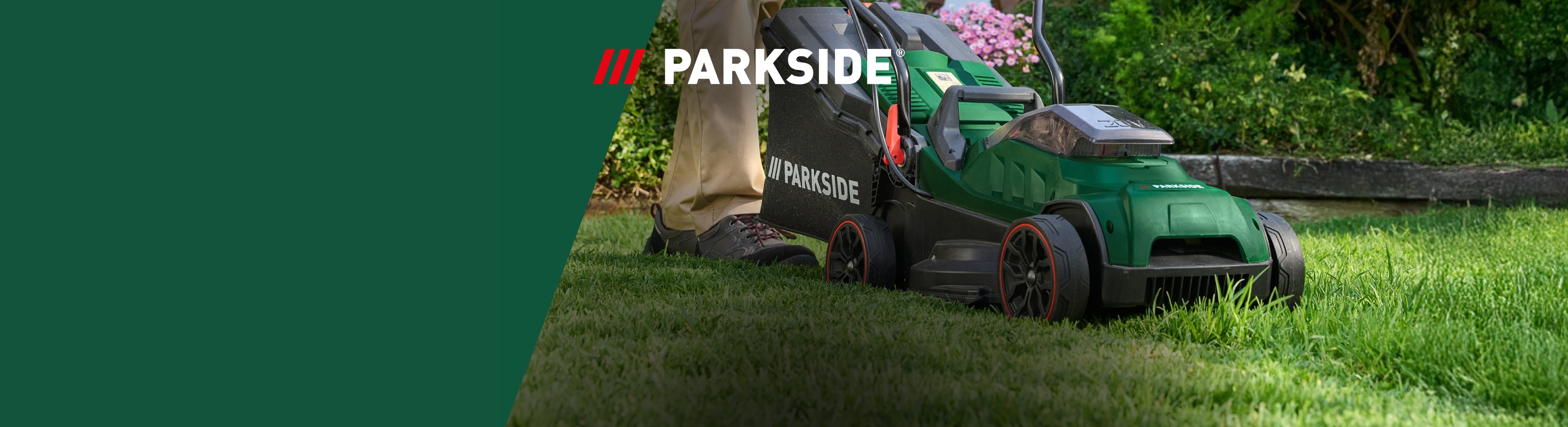 Ein Mann mäht den Rasen mit einem grünen Rasenmäher in einem sonnigen Garten.