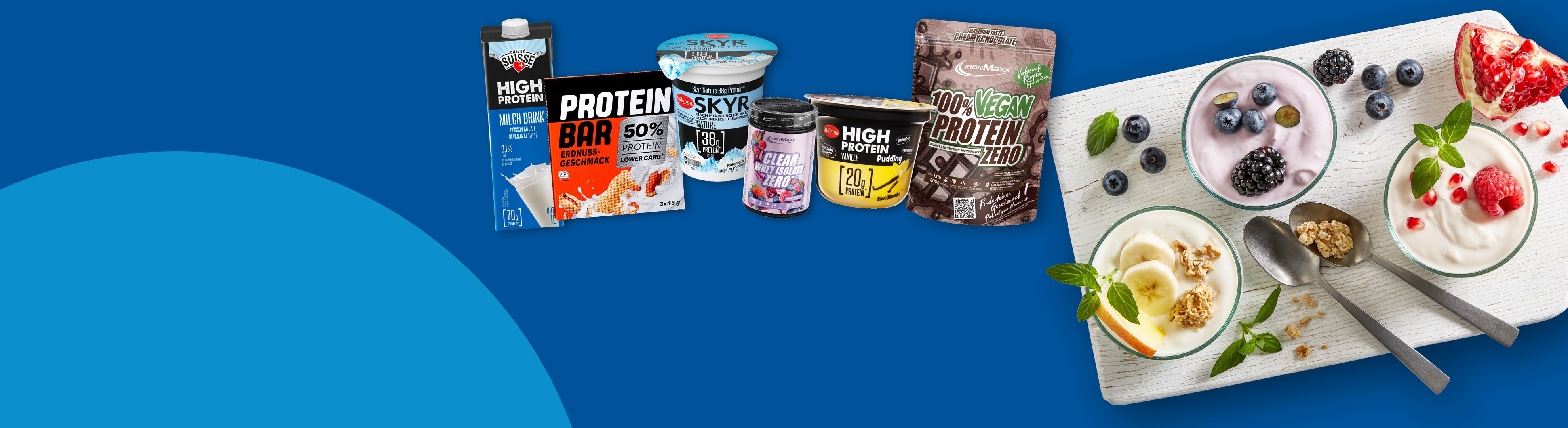 Eine Auswahl an proteinreichen Produkten, darunter Milchgetränke, Riegel, Skyr-Joghurt und Proteinpulver, teilweise in Schalen serviert.