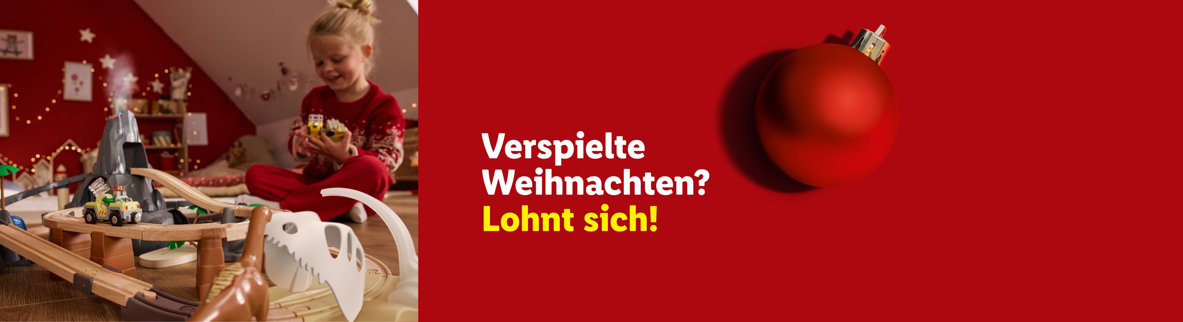 Mädchen spielt mit Spielzeugeisenbahn und Vulkan. Text: Verspielte Weihnachten? Lohnt sich!