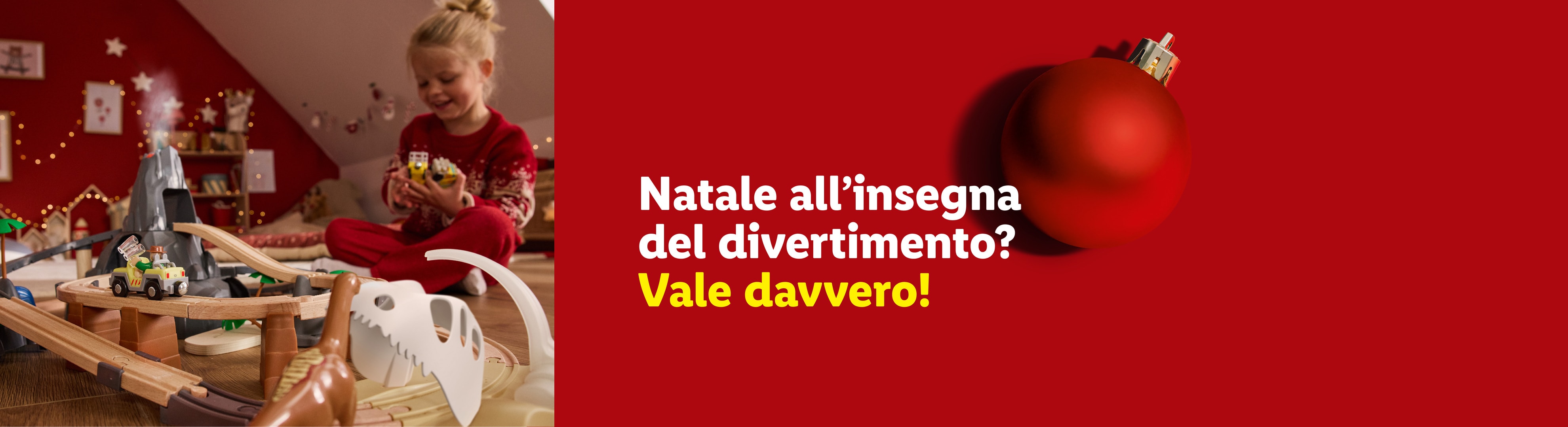 Bambina gioca con trenino e pista dinosauri, testo: Natale all'insegna del divertimento? Vale davvero!