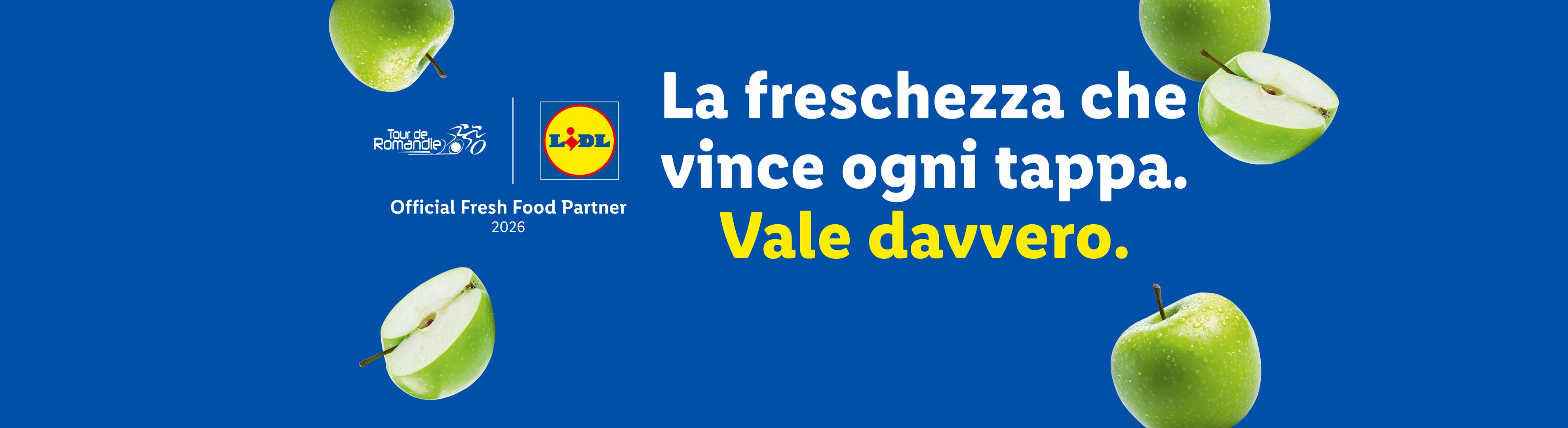 Mele verdi su sfondo blu con il testo 'La freschezza che vince ogni tappa. Vale davvero.'
